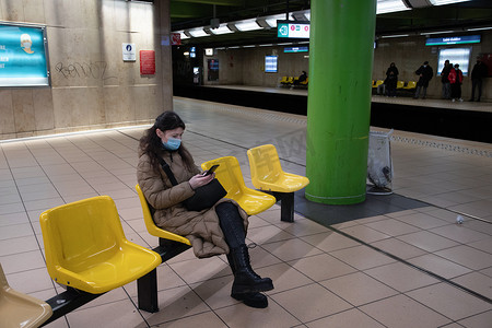 一位身穿温暖羽绒服、配有绿屏智能手机的年轻女子坐在地铁里