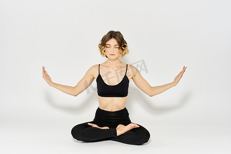 穿着深色衣服的女人坐在地板上，腿部紧身裤的冥想练习
