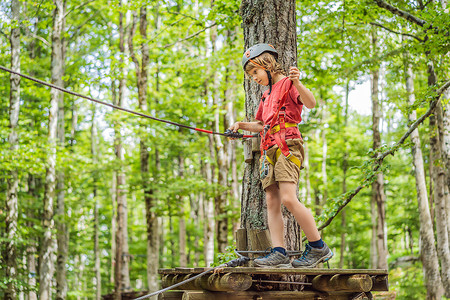 戴着头盔的快乐孩子，健康的少年男学生在夏日在攀岩冒险公园享受活动