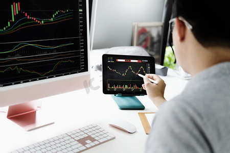 投资专业人士将笔放在电脑显示器上分析股市以获取利润。