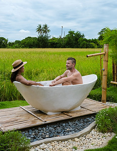 泰国一家寄宿家庭度假时，浴缸里的男男女女有绿色的稻田