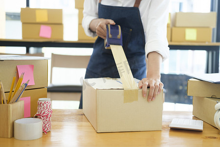 女性在线企业主包装订单箱以进行调度。