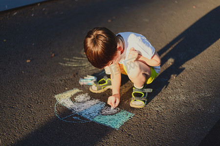 蜡笔小新标签摄影照片_一个男孩用蜡笔在沥青上画出一种生活方式。