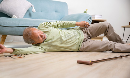 骨质疏松海报摄影照片_亚洲老人用木拐杖摔倒后躺在地板上