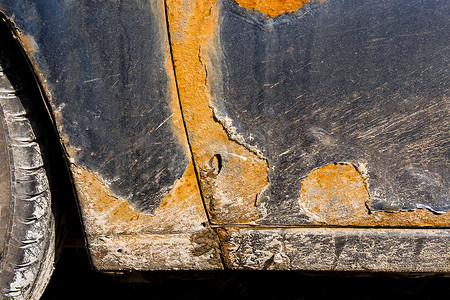 一辆肮脏的旧损坏汽车的司机门上有锈迹和磨损痕迹。