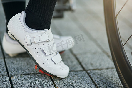 春天户外运动女摄影照片_女自行车手穿着自行车鞋站在自行车旁的腿部特写