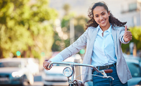 一辆自行车、竖起大拇指、快乐的女商人在城市里骑行以获取健康或健身。