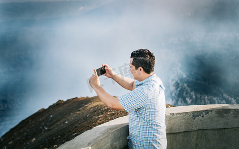 在火山观景点拍照的年轻游客。