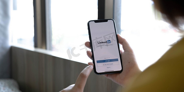 泰国清迈，2022 年 7 月 12 日：一位女士在屏幕上拿着带有 LinkedIn 应用程序的 Apple iPhone Xs。LinkedIn 是一款用于智能手机的照片共享应用程序。