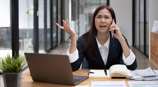 压力重重的亚洲女商人或女性营销经理在电话中与同事争论。