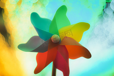 五颜六色的彩虹风车玩具与金色散景抽象有趣的背景。