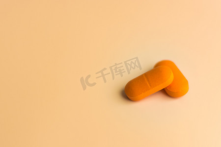 柔和的橙色背景上的两个大橙色药丸。