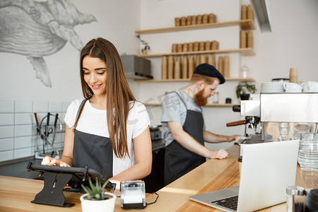 咖啡经营理念-美丽的白种人调酒师咖啡师或经理在现代咖啡店的数字平板电脑菜单中发布订单。