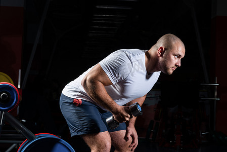 男性健美运动员在健身房里用哑铃进行锻炼