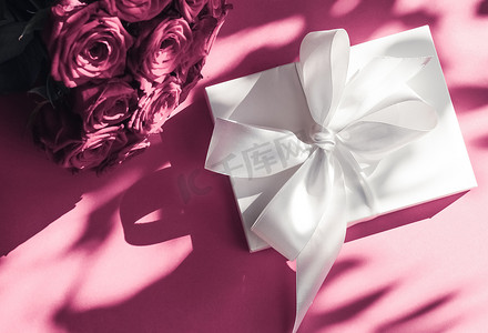 豪华假日丝绸礼盒和粉色背景玫瑰花束、浪漫惊喜和鲜花作为生日或情人节礼物