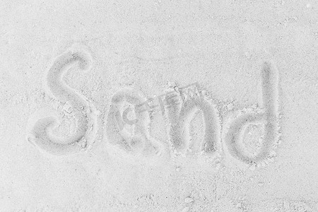 沙滩背景摄影照片_沙子这个词写在白色的沙滩背景上。