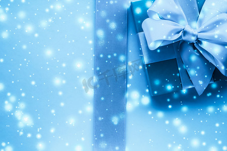 冬季节日礼物和冰冻蓝色背景下的发光雪，圣诞礼物惊喜
