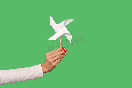女性手臂将风车玩具放在棍子上的特写，绿色背景中隔离的折纸手磨机