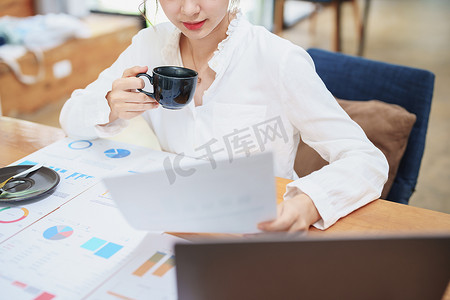 在电脑上工作、编制预算文件和喝咖啡的女性