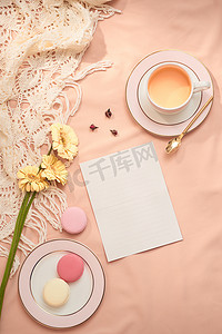 浅色背景中的信封、鲜花和马卡龙以及一杯茶