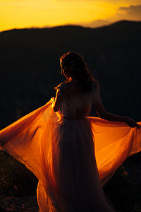 夕阳西下，新娘手挽裙摆站在山上