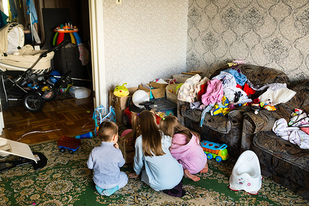 三个面目全非的孩子在肮脏杂乱的房间里玩耍