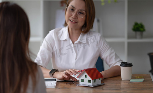 房地产经纪人或保险代理人在办公室内处理房屋模型和房屋房地产销售合同、抵押贷款审批房屋贷款和保险概念。