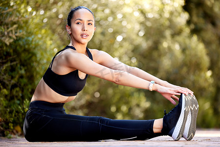 一位健康的年轻混血女性在户外运动时触摸脚部以伸展腿部进行热身，以防止受伤。