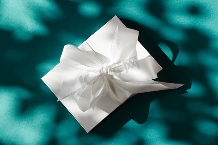 翠绿背景上带丝带和蝴蝶结的豪华假日白色礼盒、豪华婚礼或生日礼物