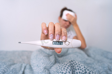 体温计摄影照片_发高烧的病妇显示温度为 38,2 的医用温度计。