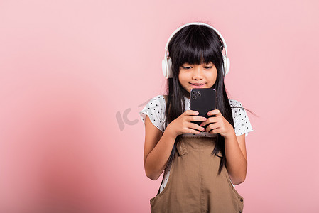 亚洲孩子 10 岁享受手机听音乐佩戴无线耳机