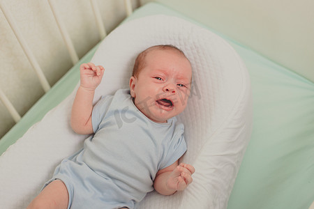 婴儿床上有一个饥饿的婴儿在哭。
