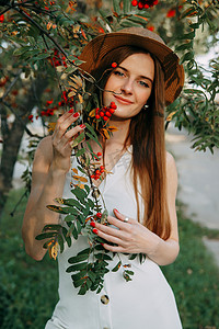 一个美丽的金发女孩，戴着帽子，长发，在秋季散步。