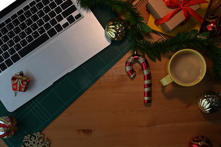木桌上的笔记本电脑、用品和圣诞装饰。