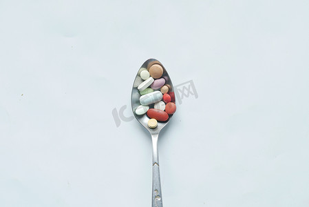 勺子白色上许多彩色药丸和胶囊的顶视图