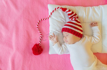 圣诞帽的婴儿摄影照片_婴儿戴着圣诞帽睡觉。