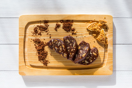 在阳光明媚的厨房里，自制巧克力香肠在木板上切片。