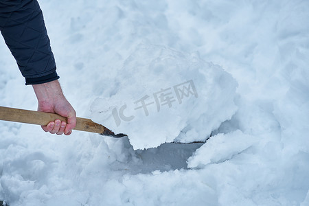 白色黑景摄影照片_男子用铲子除雪，乡村冬景
