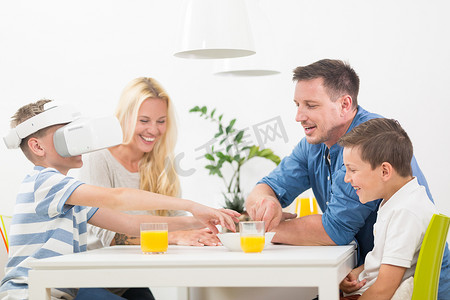 快乐的家庭在家里的客厅沙发上使用虚拟现实耳机玩游戏