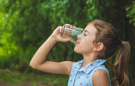 小女孩喝水摄影照片_小女孩从玻璃杯里喝水。