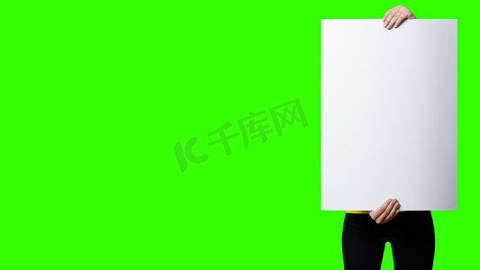 招牌海报摄影照片_美丽的女人拿着绿色屏幕背景上的空白招牌。