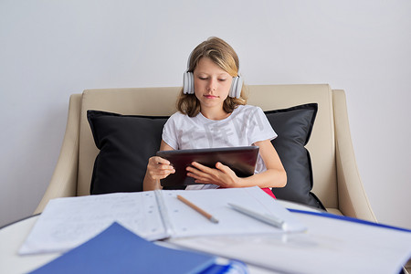 女孩在家上网学习，孩子戴着耳机戴数字平板电脑