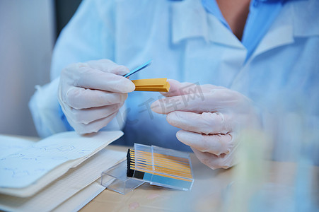 实验室技术人员戴着医用手套，拿着装有石蕊纸的容器，用于测量 PH、碱度、酸度