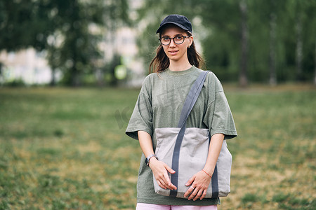 戴眼镜的年轻女子拿着空棉质生态袋，模型设计。