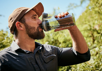 喝水的男人摄影照片_健美男子外出远足时喝水的特写。