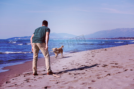 带着狗在沙滩上享受空闲时间的男人