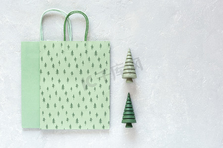 灰色背景中的绿纸圣诞袋和木制圣诞树