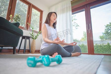 美丽的亚洲女性在家练习瑜伽时保持冷静和冥想，以追求健康的潮流生活方式