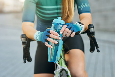 春天户外运动女摄影照片_白天，专业女自行车手拿着水瓶、休息、站在户外骑自行车的短片