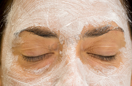 皮肤斑点摄影照片_女人用泥包闭上眼睛和额头，正面